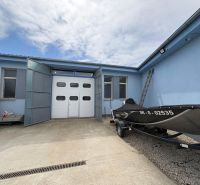 Warehouse and hall building in Orechová Potôň with a parked boat on a concrete surface.