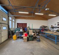 Interior of warehouses and halls with workbenches, tools, and stored materials.