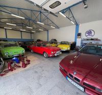 Warehouses and halls with vintage cars and auto parts on a floor with wooden decor.