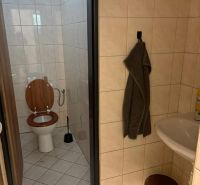Bathroom with toilet, sink, towel, and bucket on the tiles in warehouses and halls.
