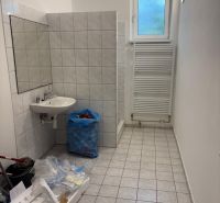 Bathroom with tiles, sink, window, and drying rack in the space of warehouses and halls.