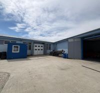 Warehouses and halls in Orechová Potôň with a parked trailer and a blue container.