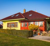 A family house in Dolný Bar with greenery and a hedge, a terrace, and a tiled roof.