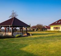 A garden with a gazebo and a family house in Dolný Bar, surrounded by a lawn.
