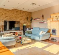 Living room in a family house with a blue sofa, large TV, and a tiled stove.