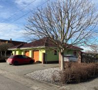 A family house in Dolný Bar with a tree in the foreground and a parked car.
