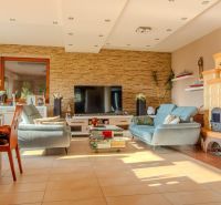 Living room in a family house with a fireplace, television, and wooden decor flooring.