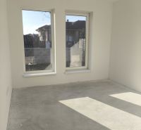 An empty room in a family house with large windows and a concrete floor.
