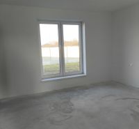 A room in a family house with a large window and a concrete floor.