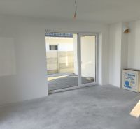 A white space in a family house with a view of the garden through glass doors.