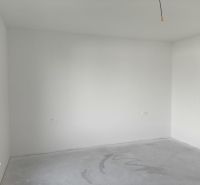 Empty room with white walls and a concrete floor in a family house.