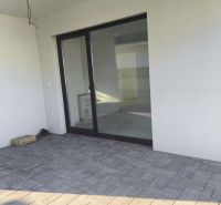 The terrace of a family house in Michal na Ostrove with tiled flooring and glass doors.