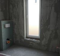 Construction of a bathroom in a family house with a window and a prepared installation system.