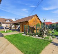 A family house in Kostolné Kračany with a lawn, a wooden extension, and a carport.