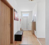 A hallway in a family house with tiles, wooden doors, and decorations on the walls.