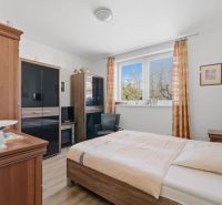 A bedroom in a family house with dark wood furniture and a wooden-patterned floor.