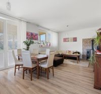Living room in a family house with wood-decor flooring and a dining area.
