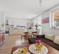 Spacious living room with kitchen in a family house, wooden decor flooring, light colors.