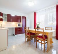 A kitchen in a family house with red cabinets, a dining table, and curtains.