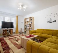 A living room in a family house with a comfortable yellow sofa and a television.