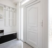 White hallway in a family house with a coat rack, storage space, and a mirror.
