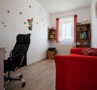 An office in a family house with a red sofa and wood-patterned flooring.