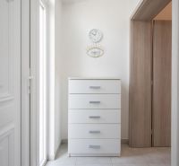 Interior of a family house with a white dresser, clock, and mirror on the wall.
