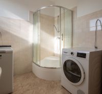 Bathroom with a washing machine and a shower in a family house, floor with wooden decor.