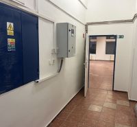 A corridor with an electrical equipment cabinet leading to commercial premises with tiling.