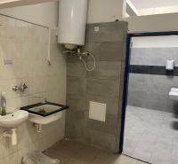 Interior of commercial premises with a sink and a boiler, adjacent to a tiled bathroom.