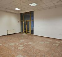 An empty commercial space with tiled flooring, white walls, and large windows.