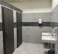 Restrooms in commercial spaces with sinks and doors for separate stalls.