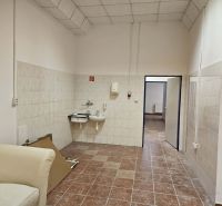 Interior of commercial spaces with sinks, tiles, and a light-colored armchair.