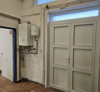 White boiler on the wall of commercial premises with a wooden decor floor.