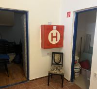 Interior of commercial premises with a fire cabinet, a chair, and storage rooms.