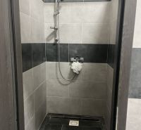 A shower corner with black and gray tiles in commercial premises.