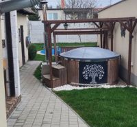 The courtyard of a family house in Dolný Štál with a hot tub under a pergola and a manicured lawn.