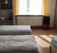 A bedroom in a family house with a wooden decor floor, beds, and a built-in wardrobe.