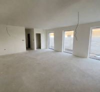 A spacious room with three windows and an unfinished floor in a family house.