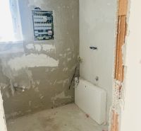 The interior of a family house with a distribution board and raw walls, showing the preparation of electrical installation.