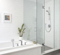 A bathroom in a family house with a bathtub, a shower corner, and tiles in light shades.