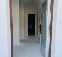 A view into the hallway of a family house with a raw concrete floor.
