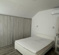 Bedroom in a studio apartment with a white bed and a built-in wardrobe.