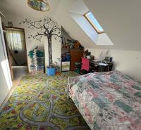 Children's room in a family house with a cheerful carpet and tree decoration on the wall.