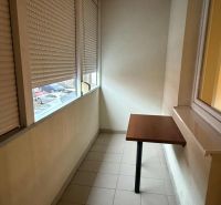 Closed terrace with cladding, folding table, and view from a three-room apartment.