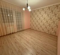 A room with patterned wallpaper, curtains, and a floor with a wooden decor in a three-room apartment.