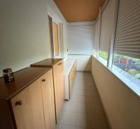 Enclosed loggia in a 3-room apartment with tiles and wooden cabinets.
