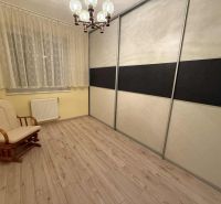 A room in a 3-room apartment with a wooden decor floor, an armchair, and a wardrobe.