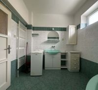 Bathroom in a family house with a washing machine, green sink, and tiles.
