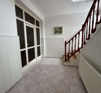 A hallway with tiles and a wooden staircase in a family house.